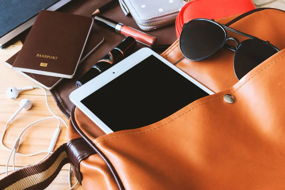 Aerial view of large carry-on bag spilling out travel gear and gadgets across the table